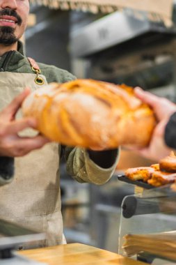 Fırında yeni pişmiş bir somun ekmeği küçük işletmeleri, zanaatkarlığı ve taze gıdanın neşesini temsil eden bir müşteriye vermek.
