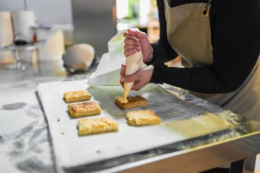 Pasta şefi ustalıkla yeni pişmiş hamur işlerinin üzerine krema döküp profesyonel bir fırın mutfağına biraz tatlılık katıyor.