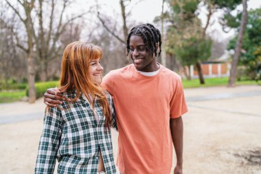 Genç, çok ırklı bir çift parkta birlikte yürüyor, birlikte vakit geçiriyorlar ve bir anlık mutluluğu paylaşıyorlar.