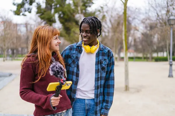 İçerik yaratıcısı olarak işbirliği yapan çok ırklı genç çift, parkın huzurlu atmosferinin tadını çıkarırken podcastları için ses kaydı yapıyorlar.