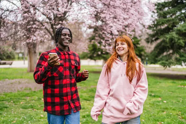 Irklar arası çiftler açık havada yemyeşil ve pembe ağaçlarla neşeyle dans ediyorlar. Mutluluk kavramı.