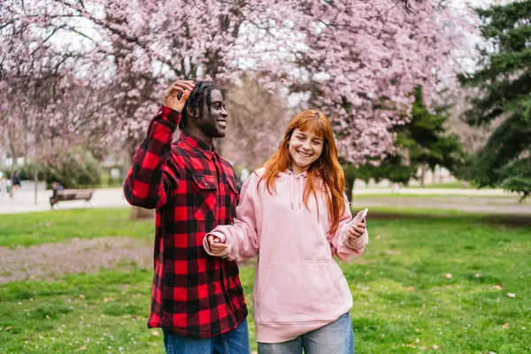 Renklerle dolu manzaralı bir parkta müzik ritmine göre hareket eden neşeli bir çift. Enerji ve mutluluk kavramı.