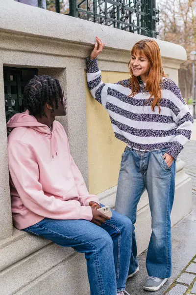 Genç, çok ırklı bir çift açık havada sohbet etmekten zevk alıyor, şehir ortamında çeşitlilik ve modern ilişkiler sergiliyorlar.