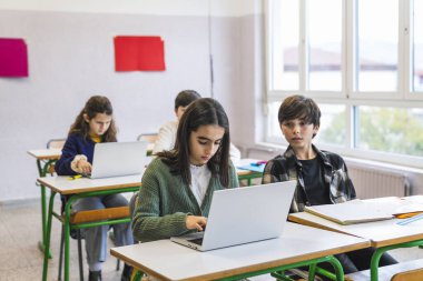 İlkokul öğrencileri bilgisayar öğreniyor ve ders sırasında sınıfta dizüstü bilgisayar kullanıyorlar.