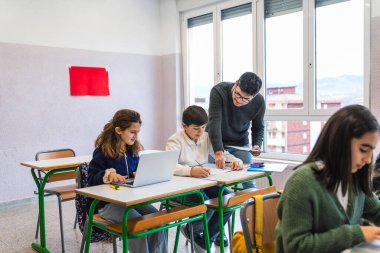 İlkokul öğretmeni öğrencilerine ödevlerinde ve derslerinde yardım ediyor.