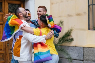 Dört neşeli gay arkadaş, evlerinin önünde toplanmış, LGBTQ yürüyüşü için gurur ve heyecan dolu, çeşitli gurur eşyalarıyla süslenmiş..