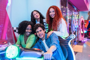 Bir grup genç arkadaş renkli ışıklarla dolu canlı bir bowling salonunda oyun oynayarak eğleniyorlar.