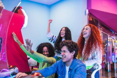 Dört genç arkadaş renkli ışıklar ve heyecanla dolu canlı bir eğlence mekanında atari salonlarında gülüp eğleniyorlar.