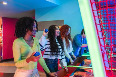 Neşeli genç arkadaşlar, boş zamanlarının tadını çıkarıyorlar. Canlı, neon ışıklı bir bowling salonunda ve atari salonunda hava hokeyi oynuyorlar.