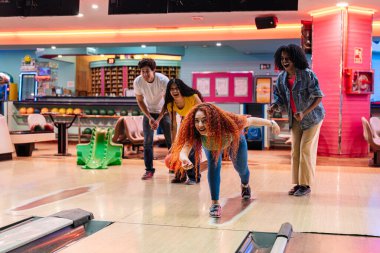 Bir grup arkadaş, neşeli bir bovling maçının keyfini çıkarıyorlar, neşeli bir ara sokakta, kahkaha, heyecan ve dostça bir rekabetle dolu.