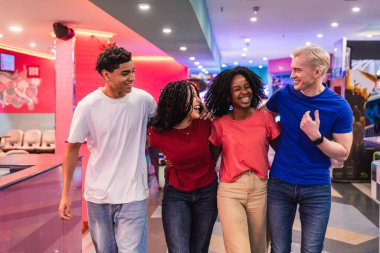 Bir grup genç arkadaş, heyecan dolu bir bowling salonunda yürürken gülüp eğleniyorlar.