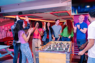 Çeşitli arkadaşlar bir bowling salonunda eğleniyor, tezahürat yapıyor ve langırt oynuyor.