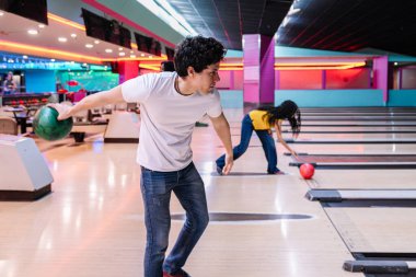 Gençler canlı bir bovling salonunun keyfini çıkarıyorlar. Top atarken gülüyorlar ve kutluyorlar.