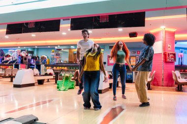 Parlak bir eğlence merkezinde bowling oynarken bir grup neşeli arkadaş grevi kutluyorlar.