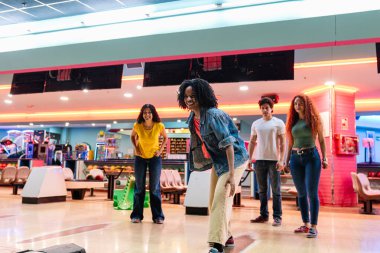 Bir grup arkadaş aydınlık, modern bir sokakta neşeli bir bovling maçının keyfini çıkarıyorlar, grevleri hedeflerken kahkaha ve heyecanı paylaşıyorlar.