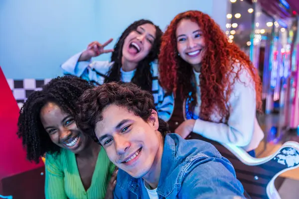 Dört neşeli genç arkadaş bir bowling salonunda ve atari salonunda eğlenirken selfie çekiyorlar.