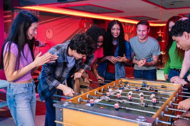 Bir grup genç arkadaş renkli bir bowling salonunda ve oyun odasında masa futbolu oynayarak eğleniyorlar.