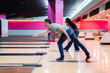 Arkadaşlar bovling oynamaktan hoşlanıyor, top oynuyor ve renkli bir bowling salonunda birlikte eğleniyorlar.