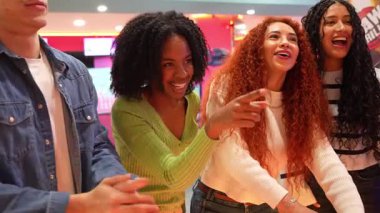 Genç yetişkinler atari oyunlarını seviyorlar, neşeli bir eğlence mekanında birlikte eğleniyorlar, yavaş çekimde yakalanmışlar.