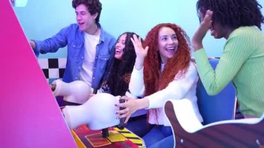 Genç yetişkinler atari oyunu oynayıp eğleniyorlar. Ağır çekimde birlikte vakit geçiriyorlar.