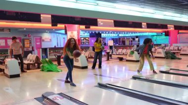 Bowling oynayan genç bir kadının yavaş çekim montajı. Arkadaşlarıyla bovling salonunda kutlama yapıyor.