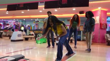 Bowling takım arkadaşları başarılı grevi coşkuyla kutluyor, zıplayarak ve tezahürat yaparak bovling salonundaki rekabetçi keyfi paylaşıyorlar.