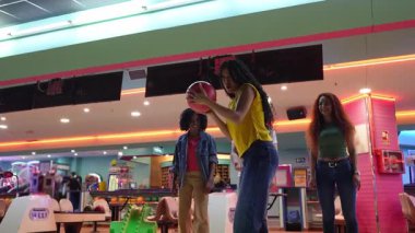 Arkadaşlar birlikte bovling oynuyorlar, yavaş çekimde grevi kutluyorlar bowling salonunda, takım başarısının ve arkadaşlığın neşeli anlarını paylaşıyorlar.