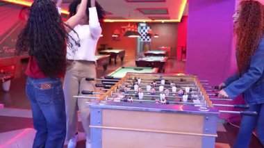 Genç yetişkinler bowling salonunda langırt oynuyorlar. Yavaş çekimde zaferi kutluyorlar.