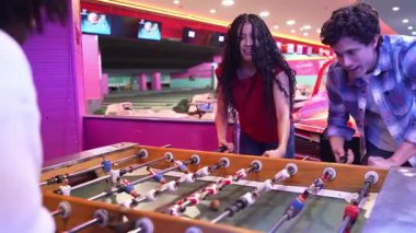 Genç yetişkinler bowling salonunda langırt oynuyorlar, zaferlerini sıcak bir kucaklaşmayla kutluyorlar.