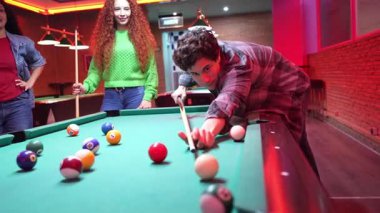 Genç arkadaşlar klasik bardaki rekabetçi bilardo oyunlarını seviyorlar, sıcak kırmızı ışıklarla aydınlatılıyorlar, keyifli dostluk ve eğlence anlarını paylaşıyorlar.