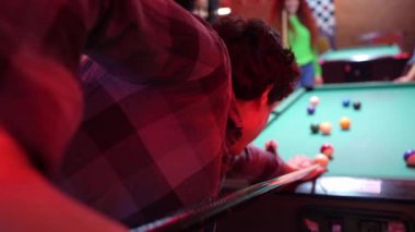 Genç yetişkinler canlı bir bar ortamında bilardo oynuyorlar. Yavaş çekim her heyecanlı anı yakalar.