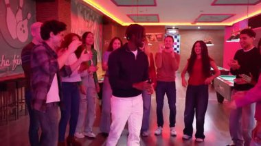 Genç arkadaşlar birlikte eğleniyor, dans ediyor ve neon ışıkları olan bir bowling salonunda kutlama yapıyorlar.