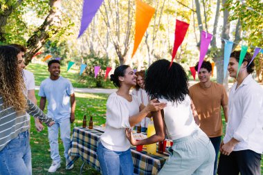 Neşeli arkadaşlar, renkli dekorasyonlar ve piknik yemeklerinin arasında mutluluk içinde neşeli bir açık hava partisinin tadını çıkarıyorlar.