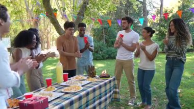 Arkadaşların parkta bir doğum günü partisinde alkışladığı ve tebrik ettiği yavaş çekim videosu.