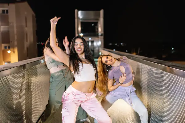 Bir grup kadın sokak dansçısı gece vakti bir köprüde koreografili dans gösterisi yapıyorlar.