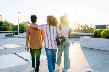 Üç genç arkadaş gün batımında şehrin çatısında kaykayla kameradan uzaklaşıyorlar, birlikte vakit geçiriyorlar.
