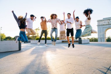 Bir grup neşeli genç öğrenci bir şehirde mezuniyetlerini kutlamak için dışarı atlıyorlar.