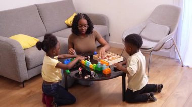 Afrikalı Amerikalı aile üyeleri renkli yapı taşlarıyla oynarken yakınlaşıyorlar, rahat oturma odası ortamında yaratıcı öğrenme aktiviteleriyle uğraşıyorlar.