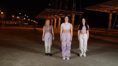 Şehir gece manzarası aydınlatan genç dans ekibi senkronize sokak dansı gösterisi yapıyor, şehir ışıkları altında tutku ve ritimle çağdaş hareketler sergiliyor.