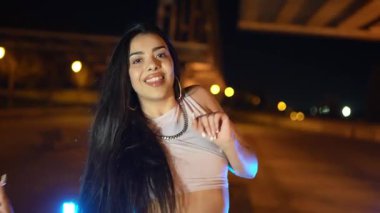 Şehvetli sokak dansçısı, gece performansı sırasında şehir köprüsü altında mavi sokak lambalarıyla aydınlatılmış, dinamik hip hop gösterisi sergiliyor.