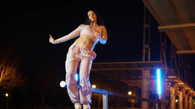 Tutkulu kadın dansçı, mavi ışık altında dinamik sokak dansı yapıyor. Enerji ve stil ile etkileyici hip hop koreografisi sergiliyor.