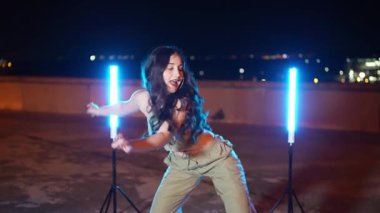 Yetenekli dansçı geceleri çatıdaki mavi neon ışıkların altında sokak dansı yapıyor.