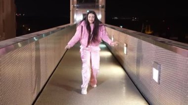 Tutkulu dansçı gece vakti aydınlık şehir köprüsünde dinamik sokak dansı hareketleri sergiliyor, özgüven ve enerjiyle dışavurumcu çağdaş koreografi sergiliyor.