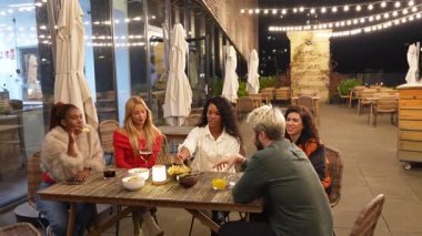 Arkadaşlar, gece sosyalleşirken gülüşlerini, içkilerini ve aperatiflerini paylaşıyorlar şehir merkezindeki şık çatı katı barında şehrin ışıklarıyla eğleniyorlar.