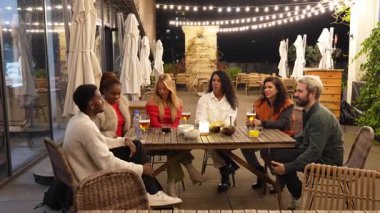 Çeşitli arkadaş grupları içki içerek kaynaşıyor, gece vakti şehir barında toplanıp gülüşmeler ve sohbetler ediyorlar.