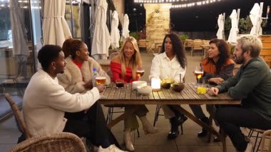 Genç, çeşitli gruplar, canlı gece yaşamının keyfini çıkarıyorlar, kokteylleri paylaşıyorlar ve şehir çatısı barında gece boyunca yumuşak sicim ışıkları altında canlı sohbetler yapıyorlar.