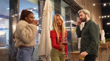 Genç arkadaşlar hareketli gece hayatının tadını çıkarıyorlar, içkilerini paylaşıyorlar, hareketli şehir barında canlı sohbetler yapıyorlar, dinamik atmosferi ve bulaşıcı enerjisi olan.