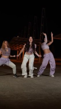 Profesyonel dans ekibi şehir gece mekanında enerjik sokak dansı koreografisi yapıyor, senkronize hareket ve sanatsal ifade sergiliyor.