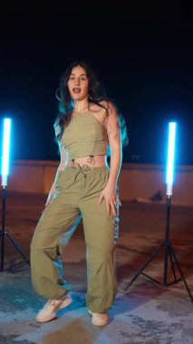 Şehrimizin çatısı üzerinde dinamik dans hareketleri yapan tutkulu kadın sanatçı, gece saatlerinde neon ışıklarıyla yıkanmış.