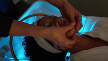 Profesyonel güzellik uzmanı tarafından güzellik kliniğinde genç bir kadına yapılan ağır çekimli yüz masajı.